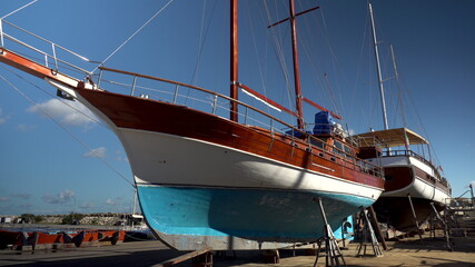 Retro ship under restoration. A wooden colorful ship stands on land. Repair of the ship. Bay