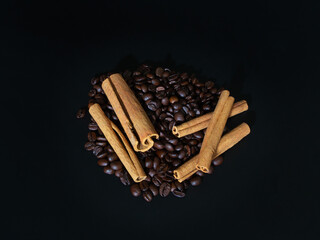 Roasted coffee beans and cinnamon on a black background.