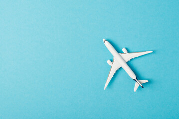 Top view photo of white airplane model on isolated pastel blue background with copyspace