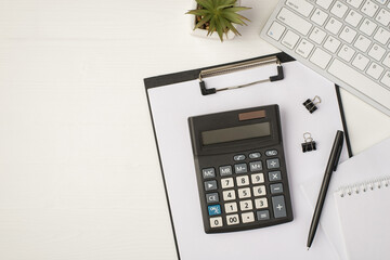 Top view photo of business workplace with keyboard plant pen binders notebook papers and calculator...