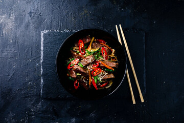 Stir fry soba noodles with beef and vegetables in wok on dark background, Asian noodles with beef WOK in black bowl - obrazy, fototapety, plakaty