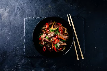 Foto op Canvas Stir fry soba noodles with beef and vegetables in wok on dark background, Asian noodles with beef WOK in black bowl © smspsy