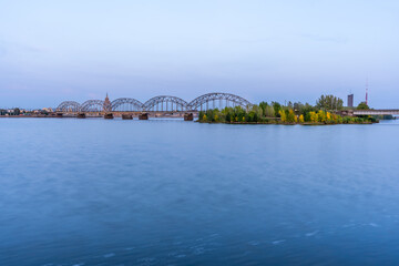 Obraz premium Cityscape with Railway Bridge in Riga, Latvia, on Blue Hour over River Daugava