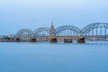 Naklejka premium Cityscape with Railway Bridge in Riga, Latvia, on Blue Hour over River Daugava