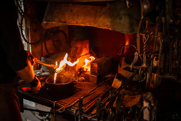 Professional blacksmith working with metal quenching hot iron part with water at forge. Handmade,...