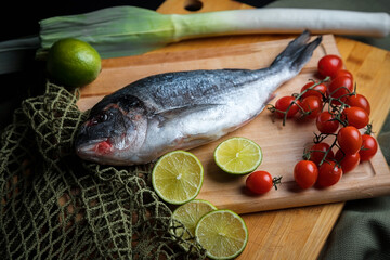 Fresh sea fish with olive oil, spices and lemon ready for cooking. Dorado or sea bream fish.