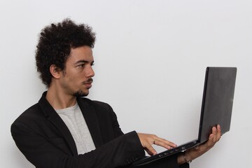 Man in black blazer on white background holding a laptop