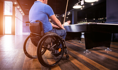 Adult men with disabilities in a wheelchair play billiards in the club