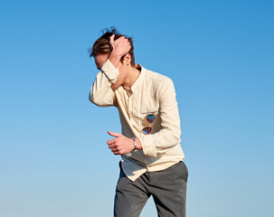 A Caucasian man from Spain covering his head with his arm on clear sky background