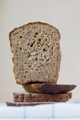 Whole grain bread with seeds dietary lies on a towel on a light background, cut, close-up, modern creative still life