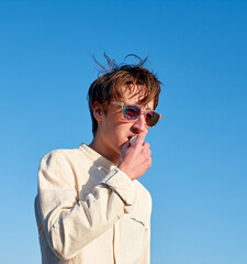 A Caucasian man with glasses from Spain eating a ripe yellow banana on clear sky background