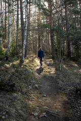 Fototapeta premium A girl with a dog walks along a path in a spring forest