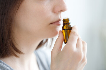 young and beautiful Caucasian women sniff a tube of aromatic oil, to check for covid-19 symptoms or a female perfumer sniffs a new perfume fragrance for women