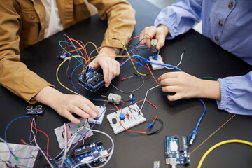 Top view close up of unrecognizable children building robots and experimenting with electric...