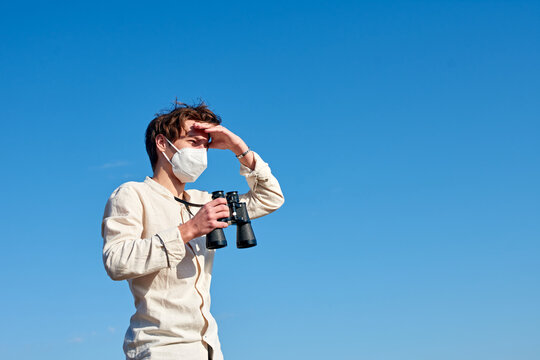 A Close Up Of A Young Man In A White Shirt Staring Into The Distance As He Shields His Face From The Sun-during Coronavirus