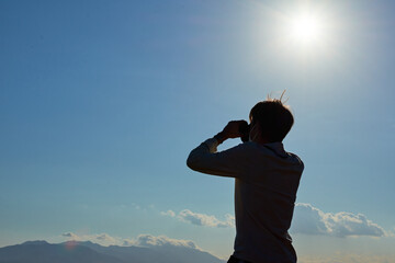 A shallow focus shot of a young man from Spain in a white shirt looking through binoculars during the pandemic