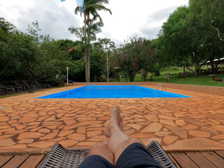 Point of view of a man lying down beside a swimming pool on a cloudy day, but very hot. - 425422790