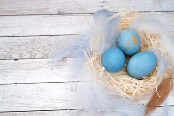 colored easter eggs with colored feathers on wooden background. easter eggs close up. Minimal...