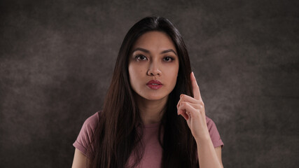 Young woman with raised index finger - studio photography