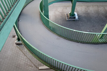 Top view over curvature pedestrian and bicycle slope way with green steel balustrade connect to...