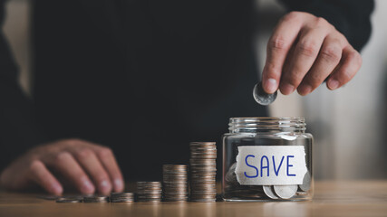 businessman putting coin into Savings money jar, business finance and saving money investment concept.