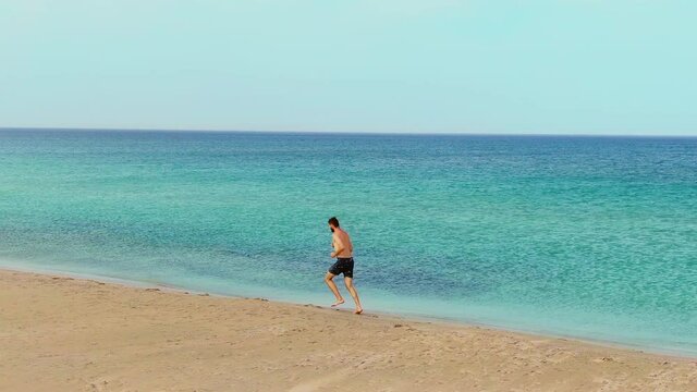 Naked man athlete jogging sand beach. People running barefoot ocean shore. Nakedness person active enjoying summer beach vacation. Male body tourist. Jogger human near sea. Runner man tourism resort.