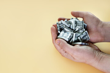 Hands hold handful of candies in form of dollars. Money depreciation and inflation concept, on yellow background with copy space
