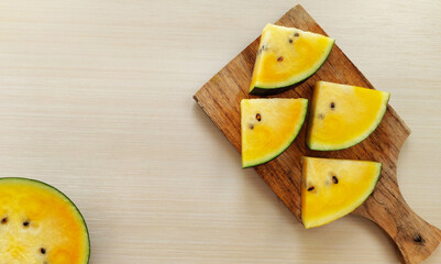 Slice of yellow watermelon on cutting board
