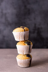 Muffins with stacked blueberries. Simple and comfortable food. Muffin tower with blueberries. Simple and comfortable food. Dark background.