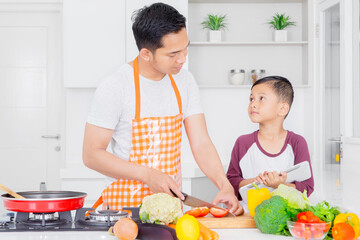 Father chatting with son while cooking in kitchen