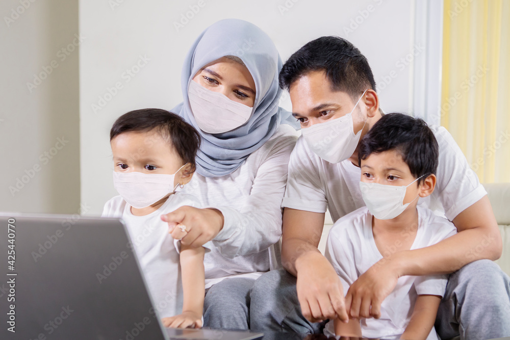 Sticker Muslim family in face mask using a laptop at home