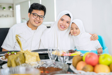 Muslim parents embracing daughter during dinner