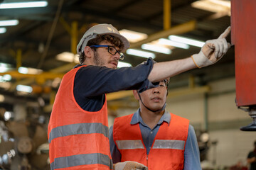 Two technician engineer working and inspecting metal component at lathes machine in industry factory.