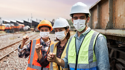 Team of Rail logistics engineers in protection clothing raising fists showing signs of joy.