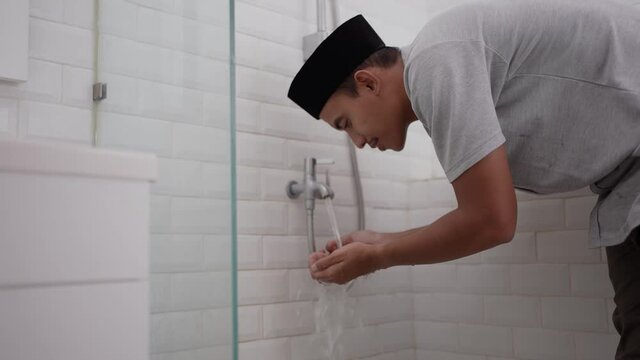 portrait of young Muslim man perform ablution (wudhu) before prayer at home