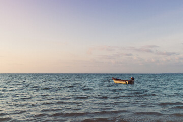 Small boat isolated on the sea on colorful sunset. Concept of lonely.