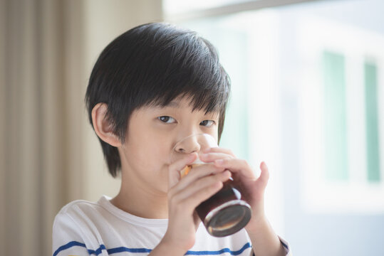Little asian boy drinking soft drink coca cola soda