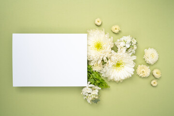 Floral flat lay with blank card on fresh green background