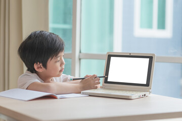 Cute Asian child learning class study online with a blank screen laptop at home .Social distancing  concept