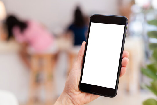 Hand man holding black mobile phone with blank white screen with blur coffee shop background. Mockup image of hand holding smartphone with blank white screen with copy space