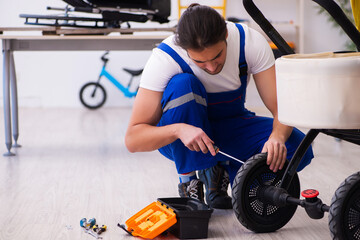 Young male repairer repairing perambulator indoors