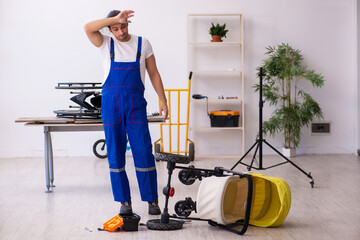 Young male repairer repairing perambulator indoors