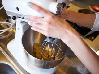 Woman hands whipping with mixer. Making dessert in modern kitchen