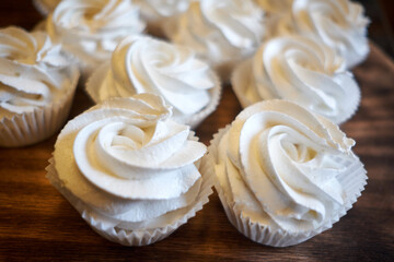 prepared meringues or marshmallows or cupcakes in pastry shop on wooden table