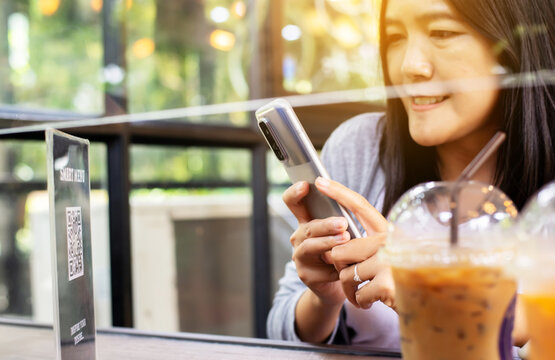 Woman using smart phone scan QR code on smart menu online to select food in restaurant