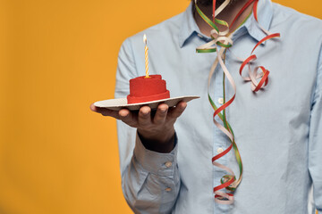 A man holding a cake in a plate and a candle from above isolated background