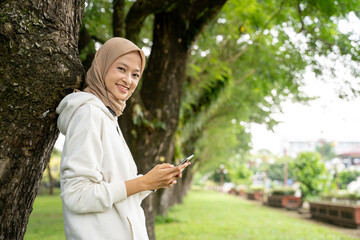 smiling beautiful young muslim woman using mobile phone during exercise break outdoor