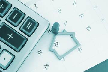 Planning sell and buy real estate. Key holder, calculator and push pin on calendar.
