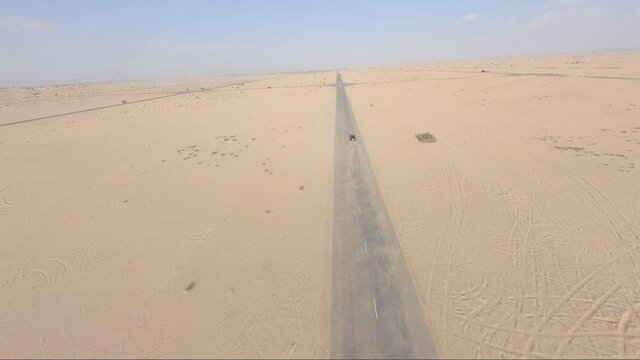 Black SUV car speeding on desert highway in United Arab Emirates, aerial view