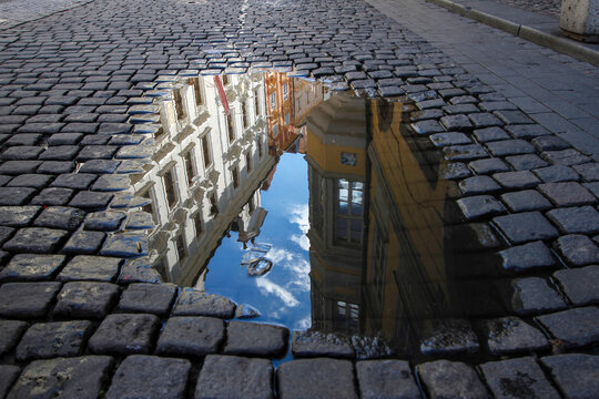 Colorful Buildings and Blue Sky Reflected in Puddle on Cobblestone Street of Prague, Czech Republic